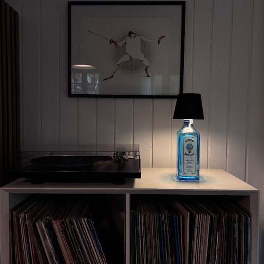 GlowBottle flaskelampe placeret i en Bombay Gin flaske, ved siden af en pladespiller